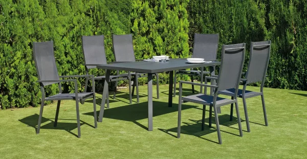 Mesa y 6 sillas para jardín. Fabricada en aluminio y textilen y pintada en color gris antracita. Está en un entorno exterior de césped.